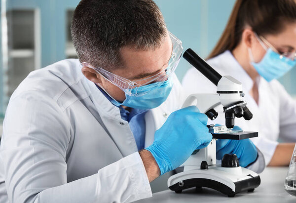 Мужчина-ученый с микроскопом работает в лаборатории
