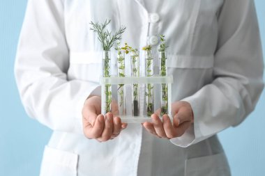 Laboratuvar çalışan test tüpleri bitkiler ile renk arka planda, closeup holding