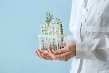 Laboratuvar çalışan test tüpleri bitkiler ile renk arka planda, closeup holding