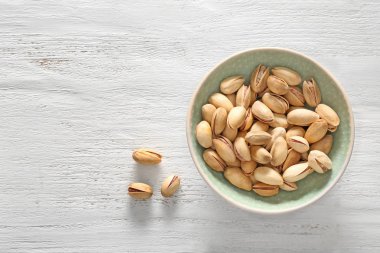 Beyaz ahşap zemin üzerinde lezzetli fıstık fındık ile kase