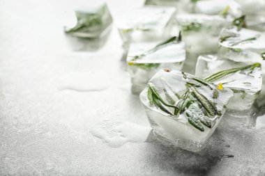 Açık gri zemin üzerinde buz küpleri içinde donmuş biberiye