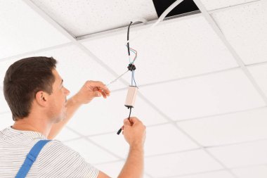 Elektrikçi içeride tavandaki voltajı ölçüyor.