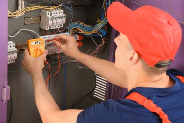 Electrician measuring voltage in distribution board clipart