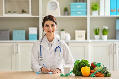 Sebze ve süt ofisinde masada oturan kadın beslenme uzmanı