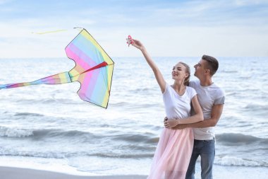 Mutlu genç çift uçan uçurtma deniz kenarında