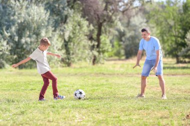 Açık havada futbol oynarken babası olan küçük çocuk