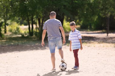 Açık havada futbol oynarken babası olan küçük çocuk
