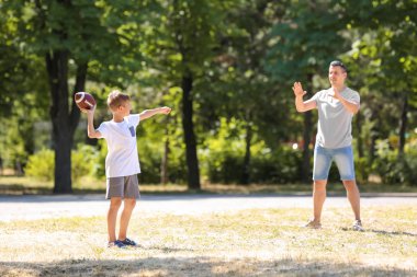 Açık havada Ragbi oynarken babası olan küçük çocuk