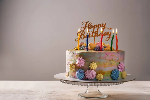 Delicious birthday cake with candles on table against grey background