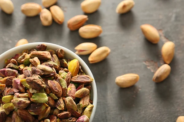 Gri arka planda, closeup lezzetli fıstık fındık ile kase