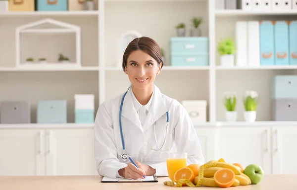 Vrouwelijke Voedingsdeskundige Zittend Aan Tafel Met Vruchten Klembord Haar Kantoor — Stockfoto