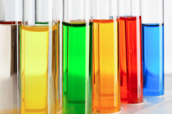 Test tubes with colorful liquids on white background, closeup