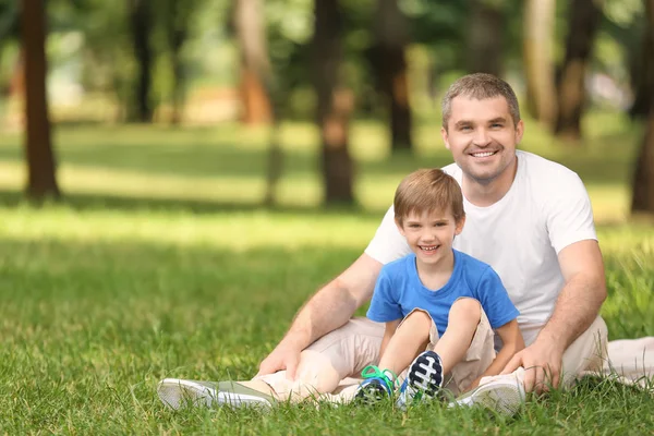 快乐的父亲与儿子休息在格子在绿色公园 — 图库照片