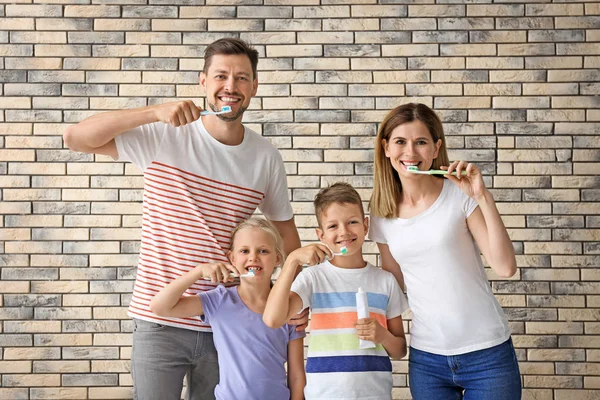 Family brushing teeth against brick wall