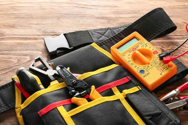 Bag with different electrician's tools on wooden background