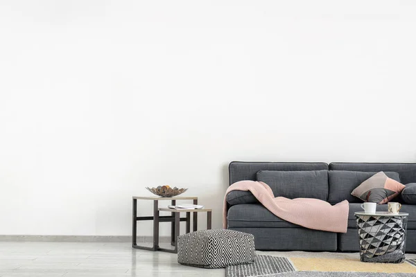 光の壁の近くの快適なソファ付けのスタイリッシュな家具 — ストック写真