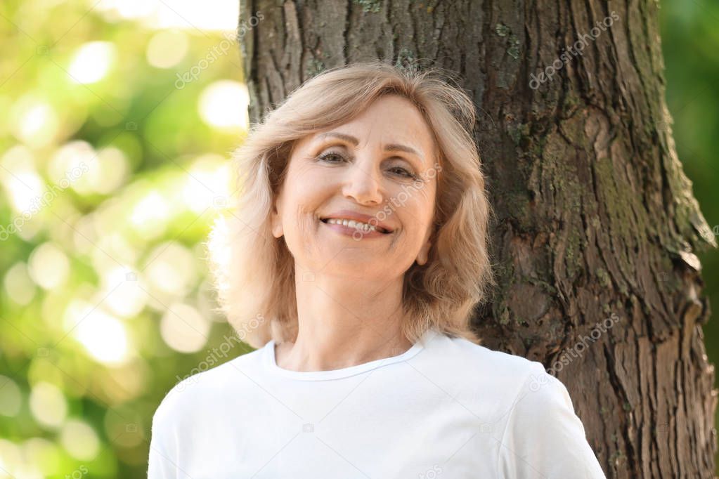 Portrait of beautiful mature woman in green park