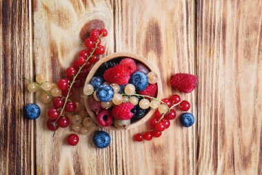 Ahşap masa üzerinde farklı olgun çilek ile kase