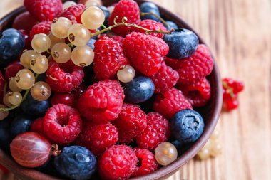 Ahşap masa, closeup üzerinde farklı olgun çilek ile kase