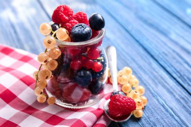 Cam kavanoz ahşap masa üzerinde farklı olgun çilek ile