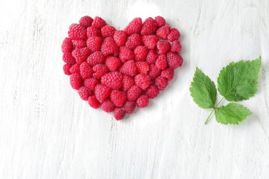 Beyaz ahşap zemin üzerinde olgunlaşmış kokulu ahududu kalp yapılmış