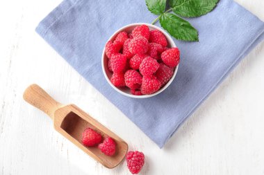 Kase ve kepçe ile beyaz ahşap masa üzerinde olgunlaşmış kokulu ahududu