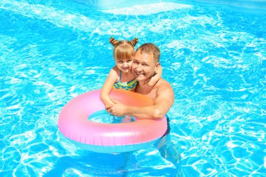Mutlu baba ve kızı yüzme havuzunda şişme yüzüklü