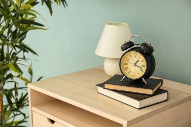 Kitaplar ve çalar saat renk duvarının yakınında içeren tablo