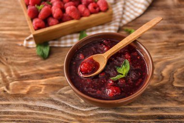 Kase ve ahşap masa üzerinde tatlı frambuaz reçeli kaşıkla
