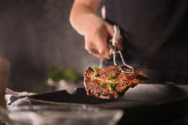 Adam mutfakta lezzetli et pişirme maşa ile