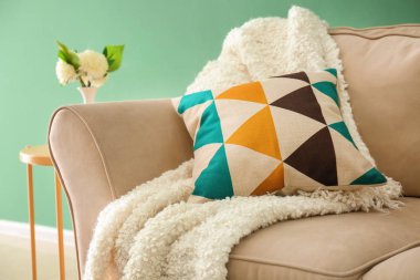 Yumuşak yastık ve ekose renkli duvarının yakınında rahat kanepe