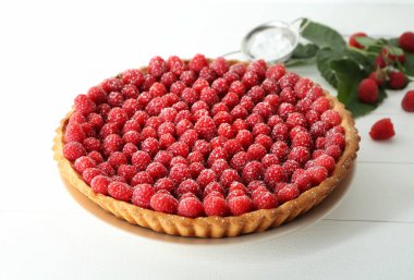 Beyaz ahşap zemin üzerinde taze ahududu ile lezzetli pasta