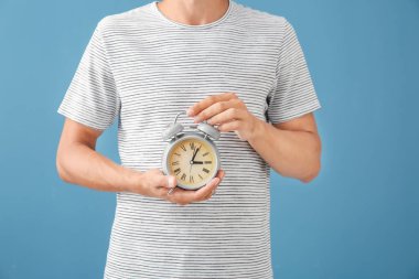Çalar saat renk arka plan üzerinde tutan adam. Zaman yönetimi kavramı