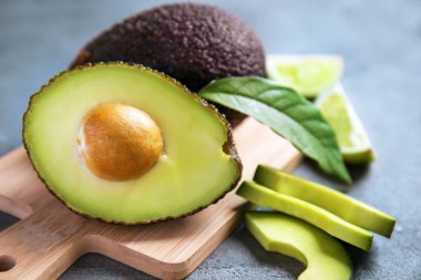 Gri dokulu arka plan üzerinde olgunlaşmış avokado ile ahşap tahta