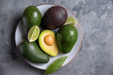 Taze olgun avokado ve kireç gri dokulu arka plan üzerinde plaka