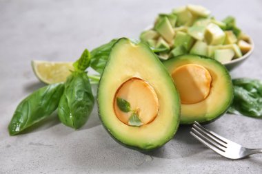 Fesleğenli lezzetli kesme olgun avokado yaprakları gri dokulu arka plan üzerinde