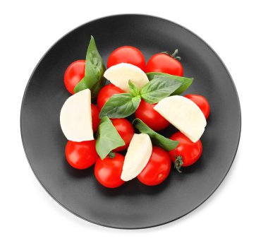 Olgun kiraz domates, mozzarella peyniri ve beyaz arka plan üzerinde otlar ile plaka