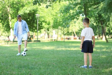 Parkta futbol oynarken babası olan küçük çocuk