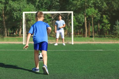 Babasıyla futbol sahada futbol oynarken küçük çocuk