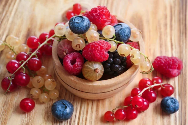 Ahşap masa üzerinde farklı olgun çilek ile kase