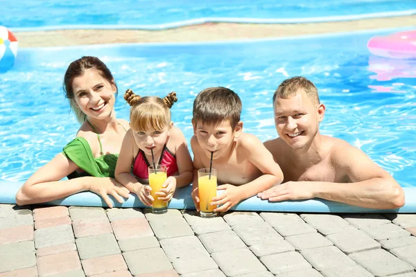 快乐的家庭与杯子果汁休息在游泳池 — 图库照片