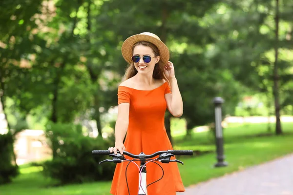 Parkta bisiklet süren genç bir kadın.