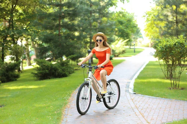 Parkta bisiklet süren genç bir kadın.