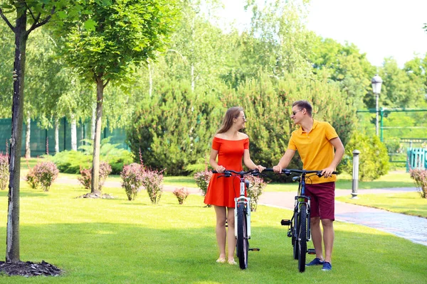 Young couple with bicycles walking in park