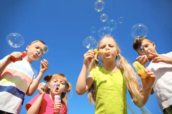 青い空を背景にシャボン玉を吹いているかわいい子供たち — ストック写真