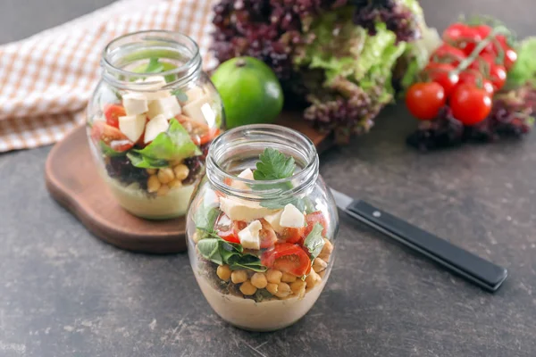 Delicious vegetable salad in jars on table