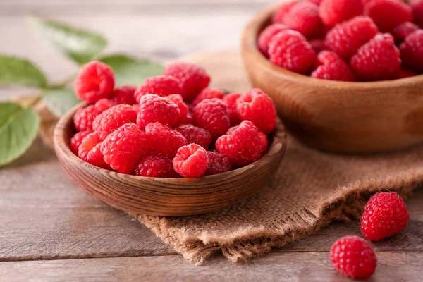 stock image Bowls with ripe raspberry on wooden table