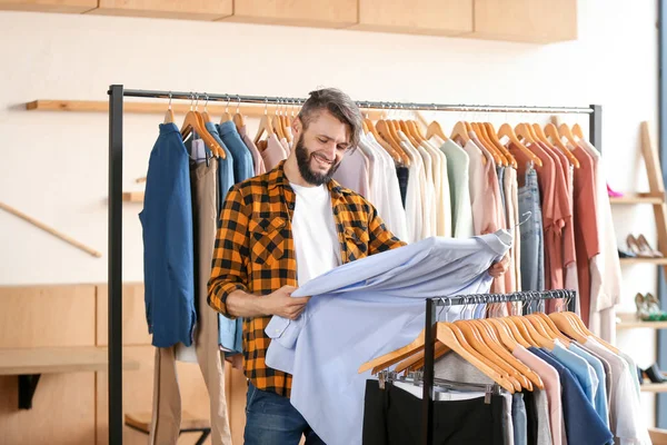 若い男が店で服を選んで — ストック写真