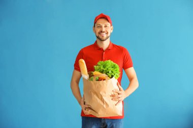 Kağıt torba renk arka plan üzerinde taze ürünlerle tutan adam. Gıda dağıtım hizmeti