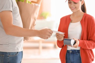 İçeride yiyecek teslimi için ödemek için banka terminal kullanan adam